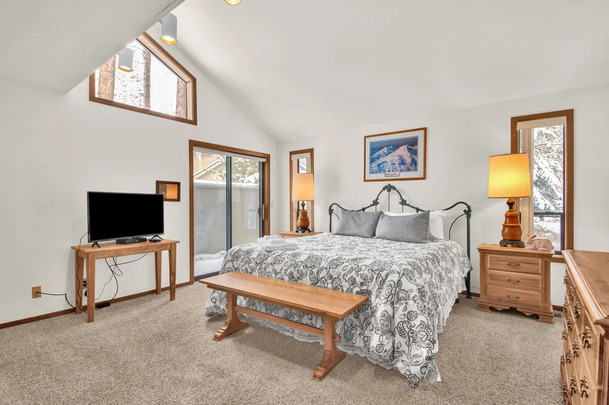 A cozy bedroom with a comfortable bed, TV, stylish lighting fixtures, and artwork on the walls. Natural light filters in through windows, creating a tranquil and inviting atmosphere perfect for relaxation and private time.
