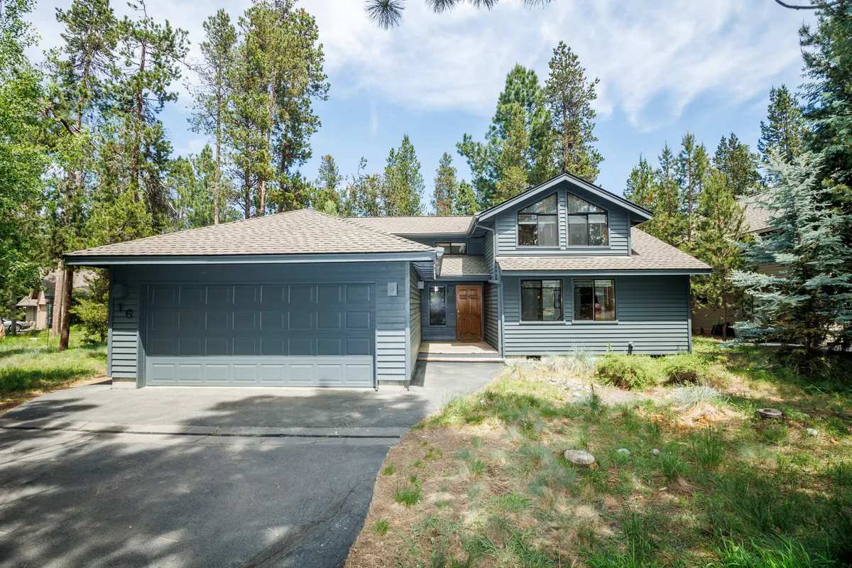 The image highlights the home's inviting front facade, featuring a wide garage, large windows, and mature trees in the surrounding yard. The spacious exterior hints at both relaxation and outdoor play for guests and their pets.