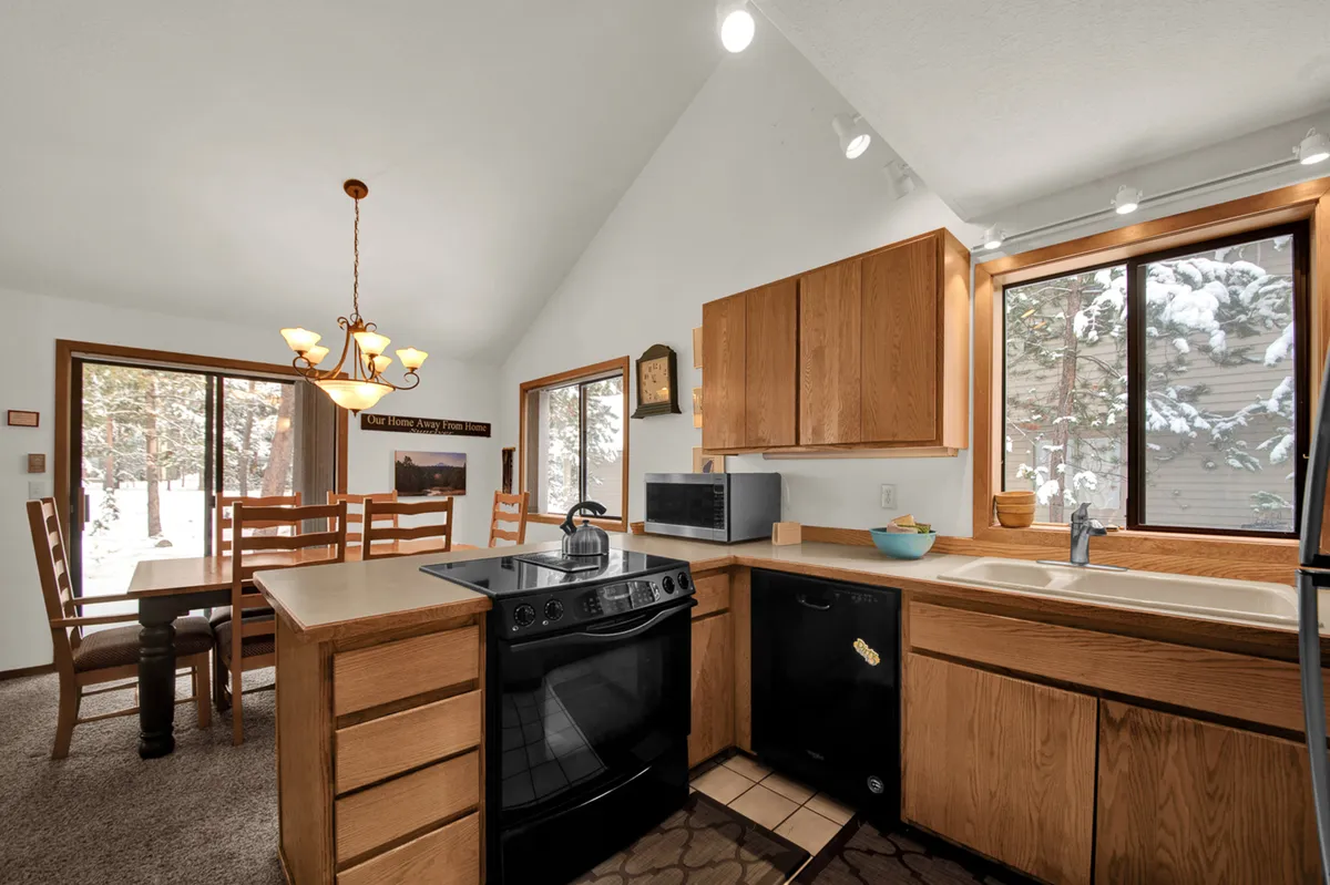 A bright open-concept kitchen and dining area featuring a large kitchen island, a dining table with seating for several people, and expansive windows flooding the space with natural light. The area is perfect for preparing and sharing meals together.